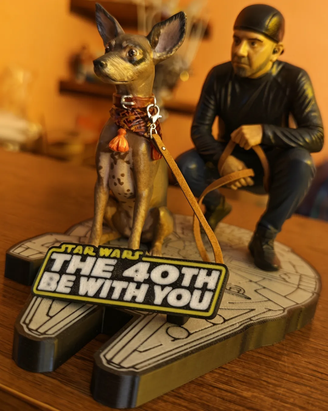 Figura semirrealista de Daniel y su xoloitzcuintle sobre base del Halcón Milenario con letrero The 40th Be With You