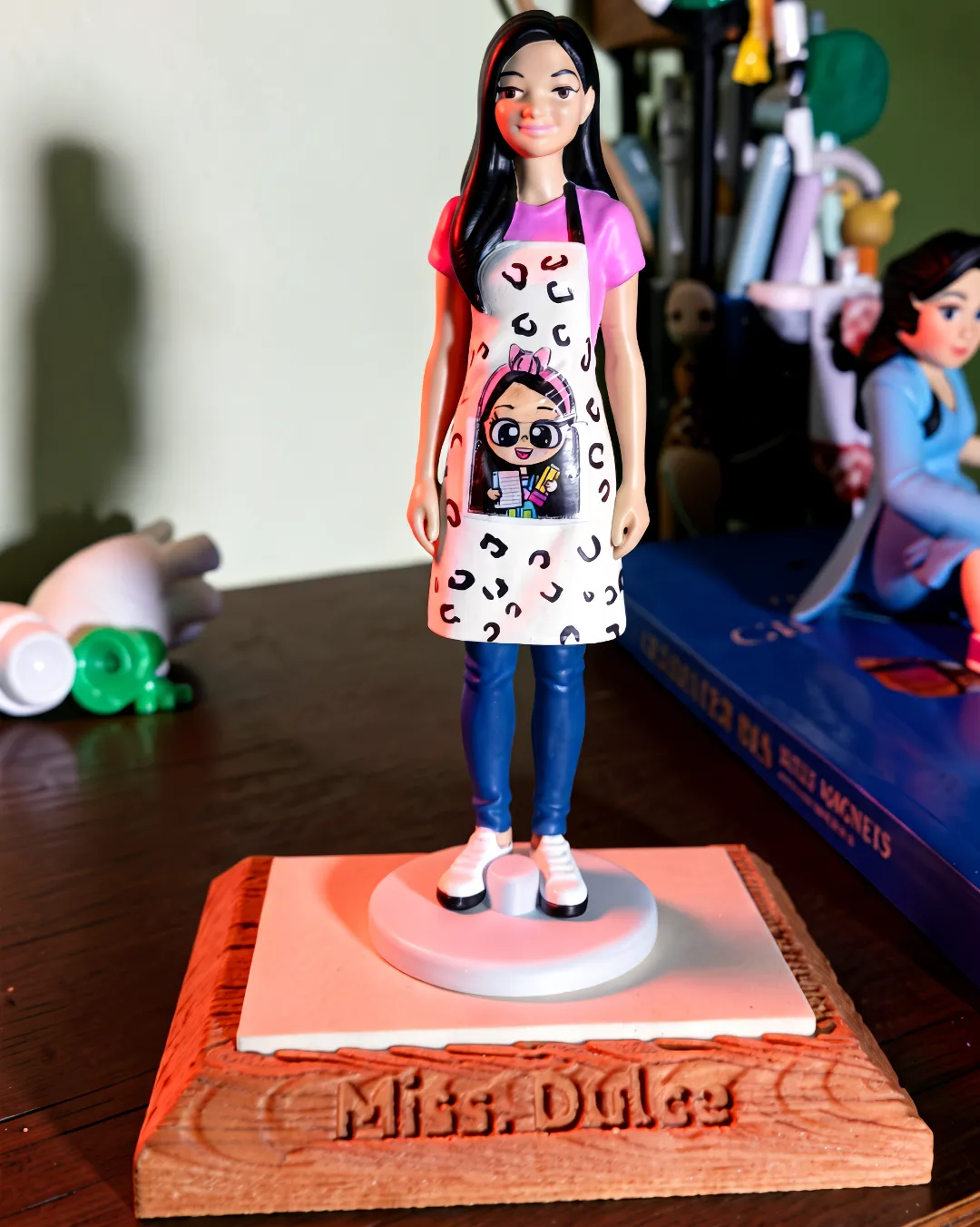 Figura conmemorativa de Miss Dulce con mandil sobre base estilo madera